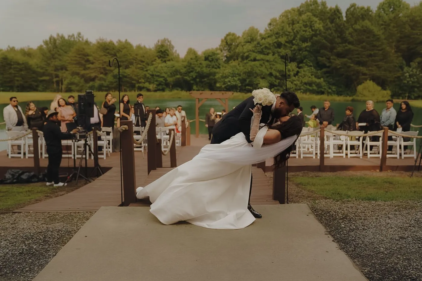 Groom dipping his bride for a kiss at the end of a lakeside ceremony