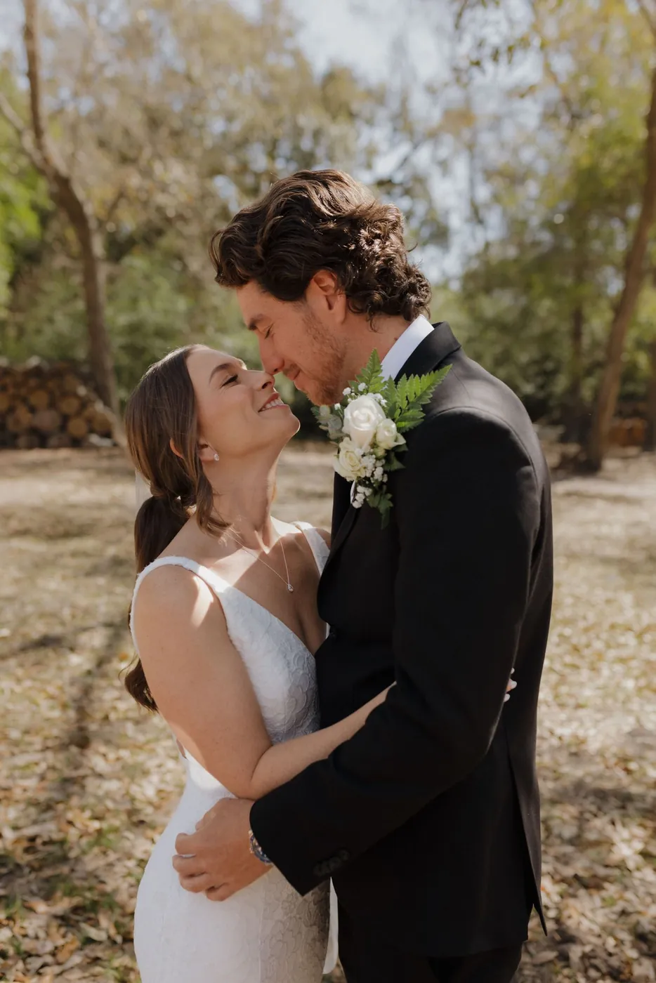 Bride and groom about to kiss under a leafy canopy